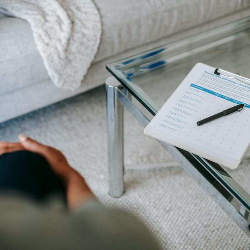 A therapy session setup with a clipboard and anxiety assessment form on a glass table.
